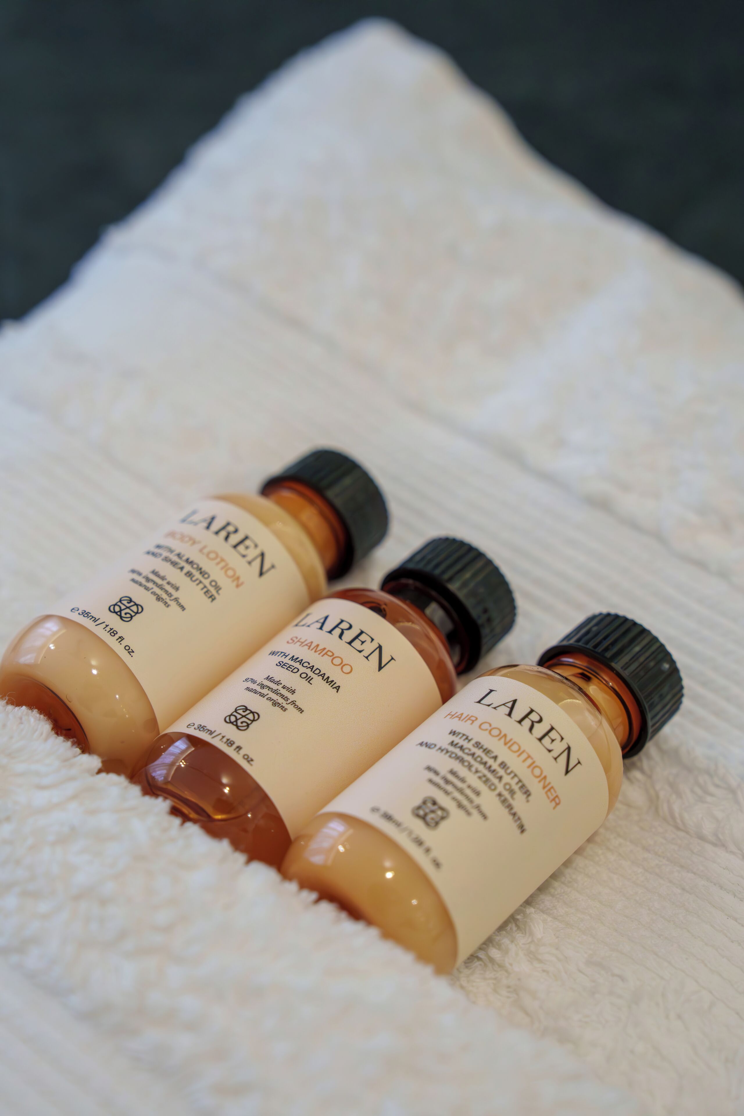 Three bottles of Laren body lotion on a white towel.