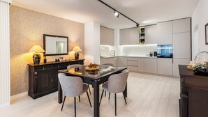 Una cocina moderna con una isla central, electrodomésticos integrados y una zona de comedor con mesa y sillas de vidrio.
