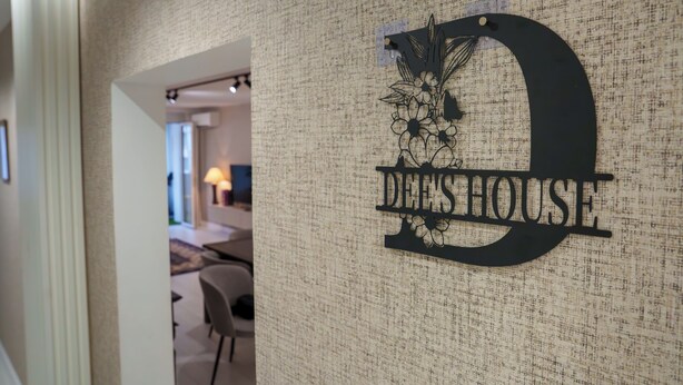 En hall med en vägg som har en intressant yta och en skylt med texten ”DEE’S HOUSE”.