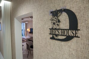 A hallway with a textured wall and a sign that reads 'DEE'S HOUSE'.
