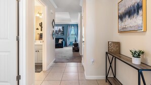 A hallway with a wooden console table, a painting, and a potted plant.