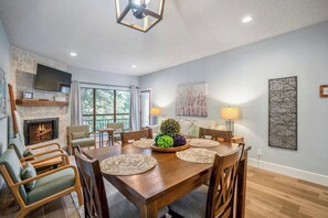 Uma sala de jantar ampla com mesa de madeira, cadeiras e lareira.
