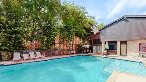 A swimming pool with lounge chairs and a covered seating area. - Camp Warnecke B111- Waters Edge - Stunning Remodel (New Braunfels)