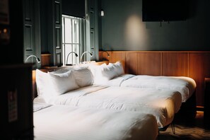 A neatly made bed in a hotel room with a wooden headboard, a flat-screen TV mounted on the wall, and a window with a view of the outside. - Converted Bar & Chinese Takeaway (Belfast)