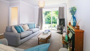 A living room with a grey sofa, a coffee table, a TV, and a fireplace. - Pebble Place (Littlehampton)
