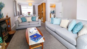 A living room with two grey sofas, a coffee table, and a bookshelf. - Pebble Place (Littlehampton)