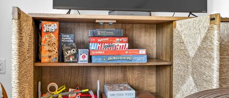 A wooden shelf with various board games and puzzles.