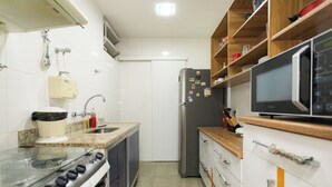 Una cocina equipada con estufa, fregadero, refrigerador y microondas.