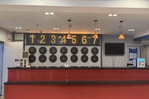 A reception desk with multiple clocks, a television, and pendant lights. - 7Days Inn Chain Hotel (Beijing West Railway Station Lizeqiao) (Beijing)