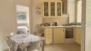 A compact kitchen with a dining area, featuring a table with chairs, a stove, and cabinets. - If you feel like (Palermo)
