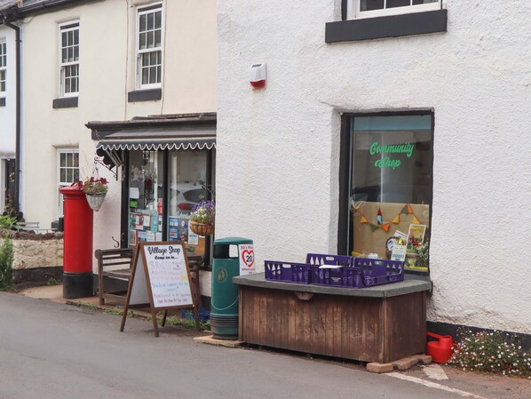 A storefront with a signboard, a wooden bench, and a red post box.