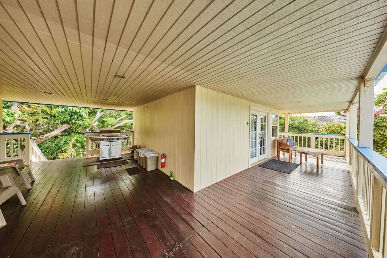 Eine überdachte Veranda mit Grill, Sitzgelegenheit und Blick ins Grüne.