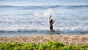 Uma pessoa brincando com água em uma praia de areia.