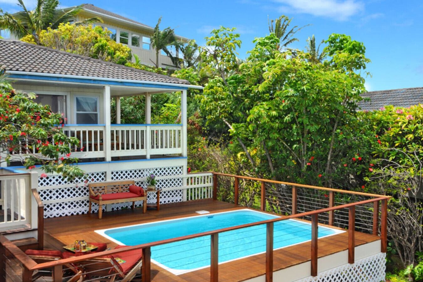 A two-story house with a wooden deck and a swimming pool.