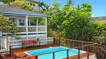 A two-story house with a wooden deck and a swimming pool.