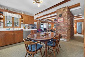 A kitchen with wooden cabinets, a dining table with chairs, and a brick wall.