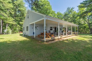 A single-story house with a covered porch, a dining area, and a barbecue setup.