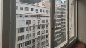 A view through a window of a multi-story building with balconies and air conditioning units.