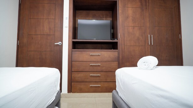 Un dormitorio con dos camas, un armario de madera y una televisión.