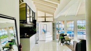 A spacious, well-lit interior with a tiled floor, a kitchen area, and a seating area with a view of the outdoors. - La Pura Vista Resort (Kralendijk)