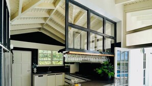 A modern kitchen with a central island, a dining area with a glass door, and a view of the outdoors. - La Pura Vista Resort (Kralendijk)