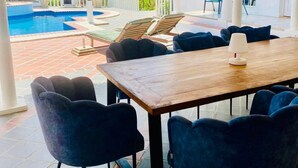 A covered outdoor area with a pool, lounge chairs, and a wooden table. - La Pura Vista Resort (Kralendijk)