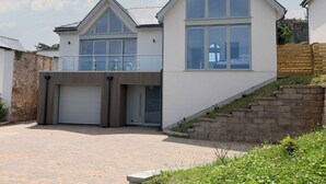 Una moderna casa a due piani con garage, ampie finestre e un balcone.