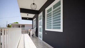 A modern building with a dark facade, white-framed windows, and a tiled balcony. - R&V Combate Beach House, 2nd Floor with Pool (Cabo Rojo)