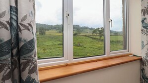 Una habitación con un ventanal grande que da a un campo verde y árboles.