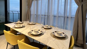 A dining area with a marble table, yellow chairs, and a view through large windows.