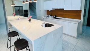 A modern kitchen with a large island, stainless steel appliances, and a wooden backsplash.