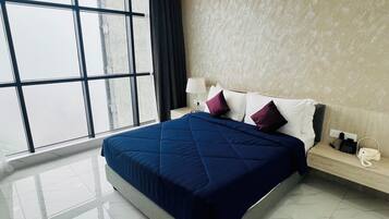A modern hotel room with a large bed, a nightstand, a lamp, and a view through large windows.
