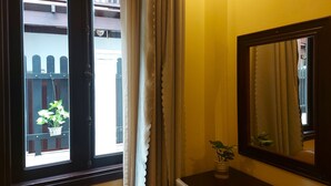 Een kamer met een raam, een spiegel en een klein tafeltje met een plant.