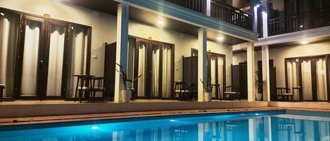 Een buitenzwembad, parasols bij het zwembad en ligstoelen