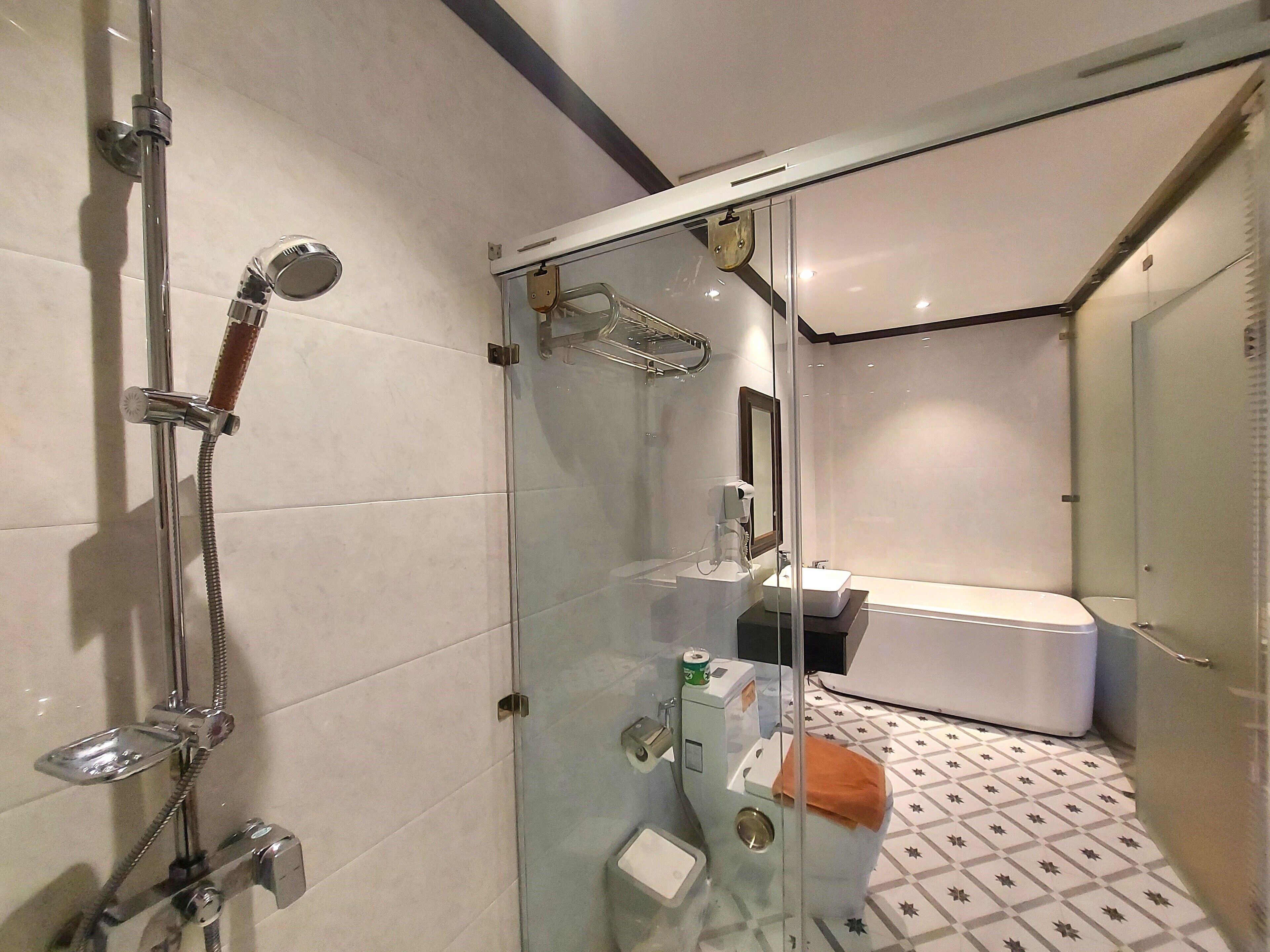 Un baño moderno con ducha envuelta en vidrio, un lavamanos blanco y una bañera.