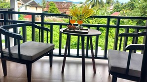 Een balkon met twee stoelen, een kleine tafel met dienblad, een plant in pot en twee drankjes.