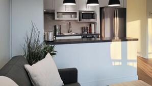 Een moderne keuken met witte kasten, roestvrijstalen apparatuur en hanglampen.