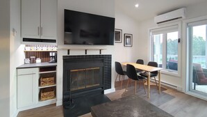 Een moderne woonkamer met een open haard, eethoek en grote ramen.