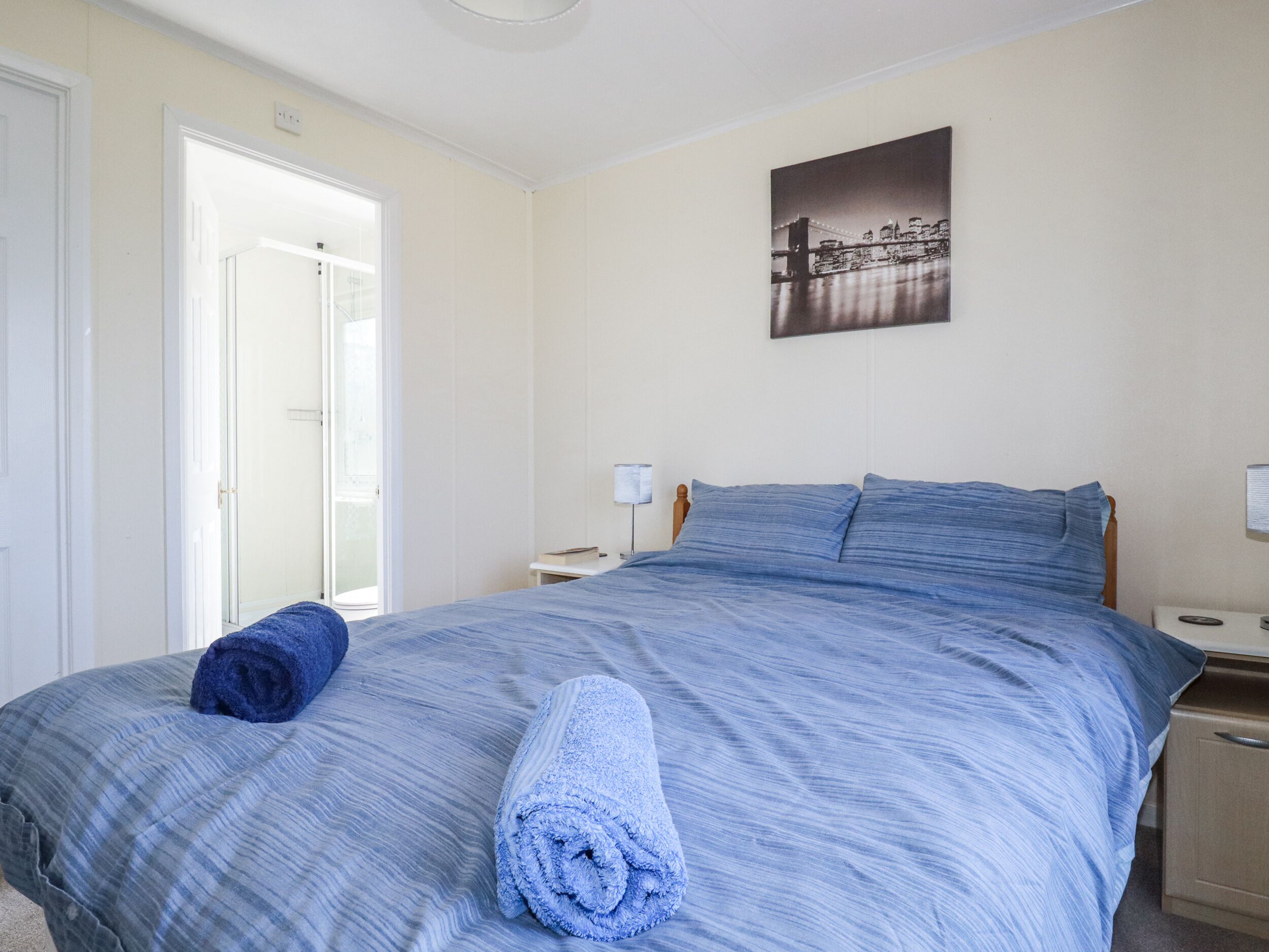 Une chambre à coucher avec un lit, une table de chevet, une lampe et une porte donnant sur une autre pièce.