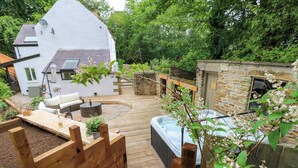 A wooden deck with outdoor seating, a hot tub, and a stone building. - White House (Durham)