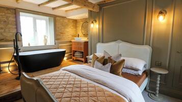 Ein Schlafzimmer mit einem großen Bett, einer Badewanne und einer Holzbalkendecke.