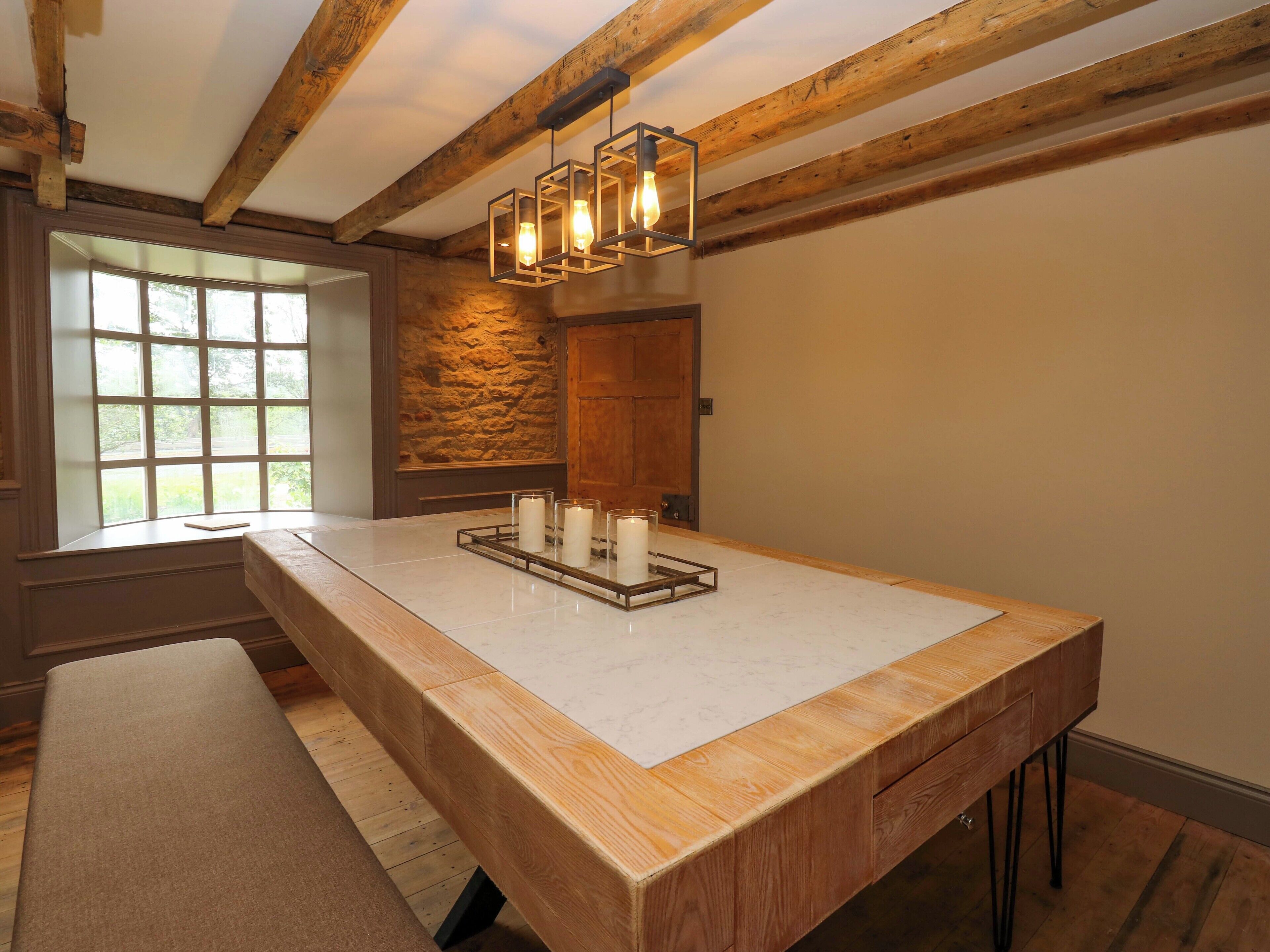 Une pièce avec une grande table en bois, un mur en pierre et une porte en bois.