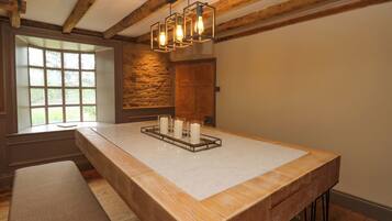 Une pièce avec une grande table en bois, un mur en pierre et une porte en bois.