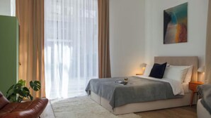 Une chambre d’hôtel moderne, équipée d’un lit, de tables de chevet, d’une chaise, d’une plante et d’un tableau au mur.