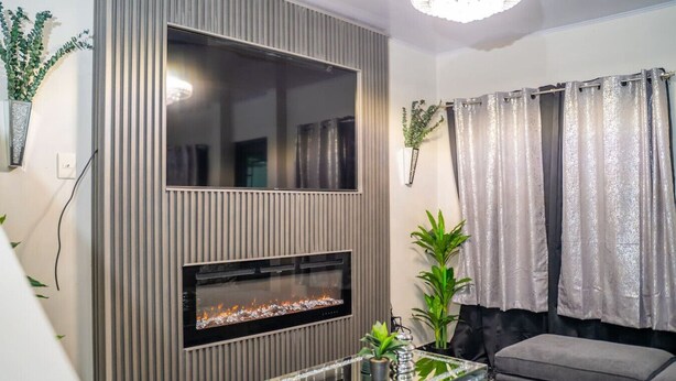 A modern living room with a built-in fireplace, a glass coffee table, and a grey sofa.