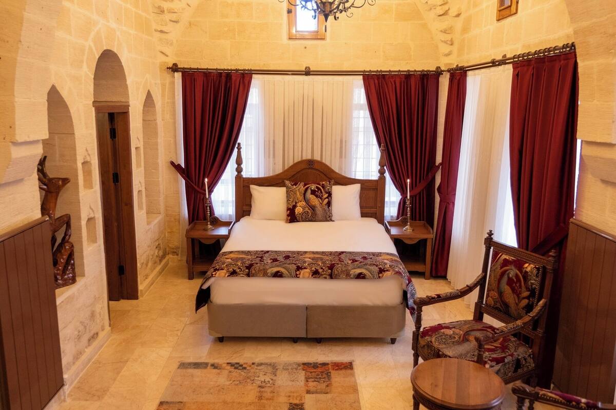 A bedroom with a large bed, two nightstands, a chair, and a small table.
