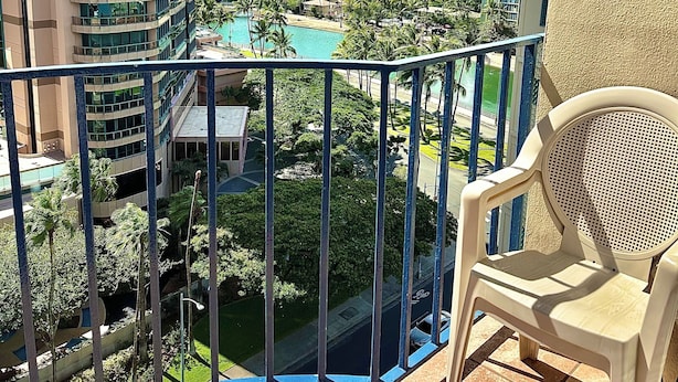 Un balcon offrant une vue sur le paysage urbain, avec de grands immeubles et un espace piscine.