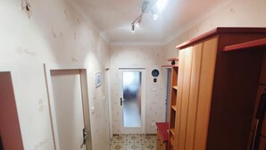 A narrow hallway with patterned floor tiles, a frosted glass door, and wooden cabinets. - Charming Vintage Vienna Getaway  67m² with A/C (Wien)
