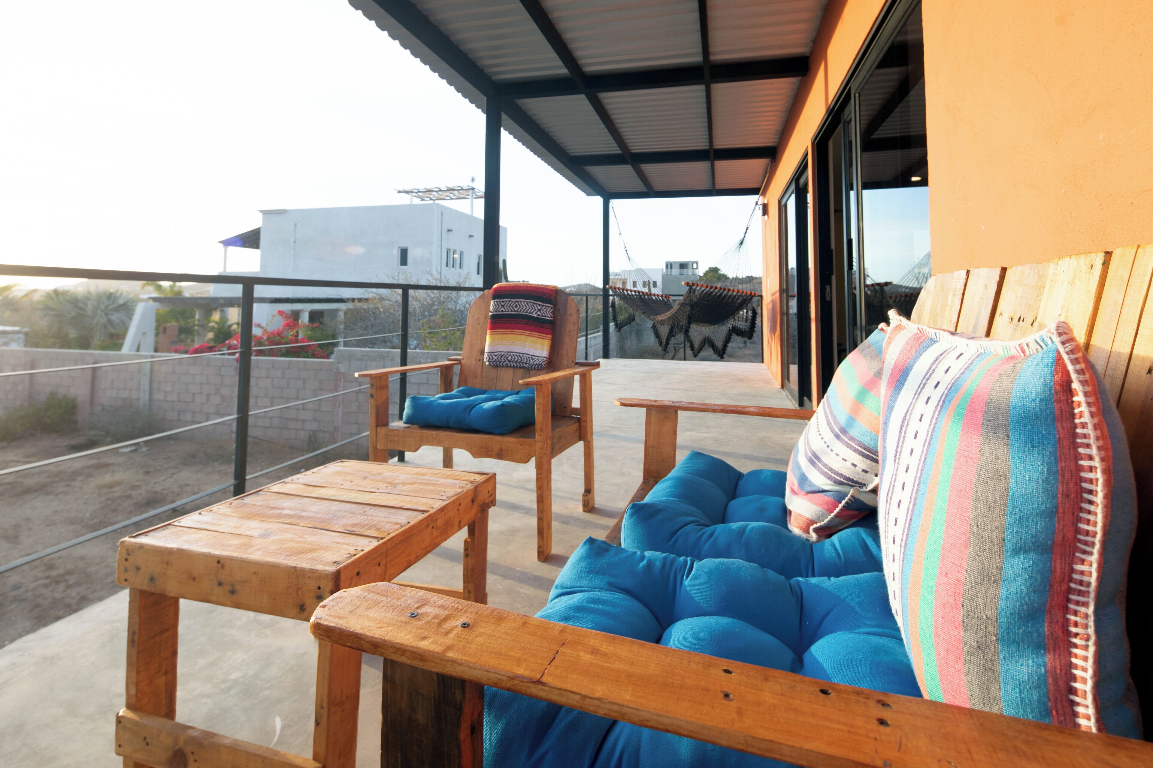 A covered outdoor seating area with wooden furniture and blue cushions.