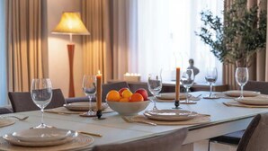 A dining table set with plates, glasses, and a bowl of fruit.